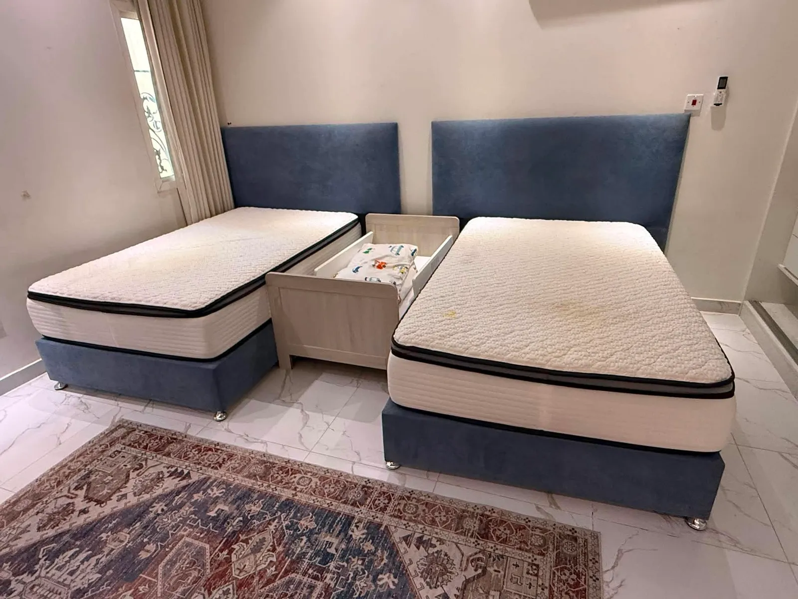 Twin divan beds with tall upholstered blue headboards