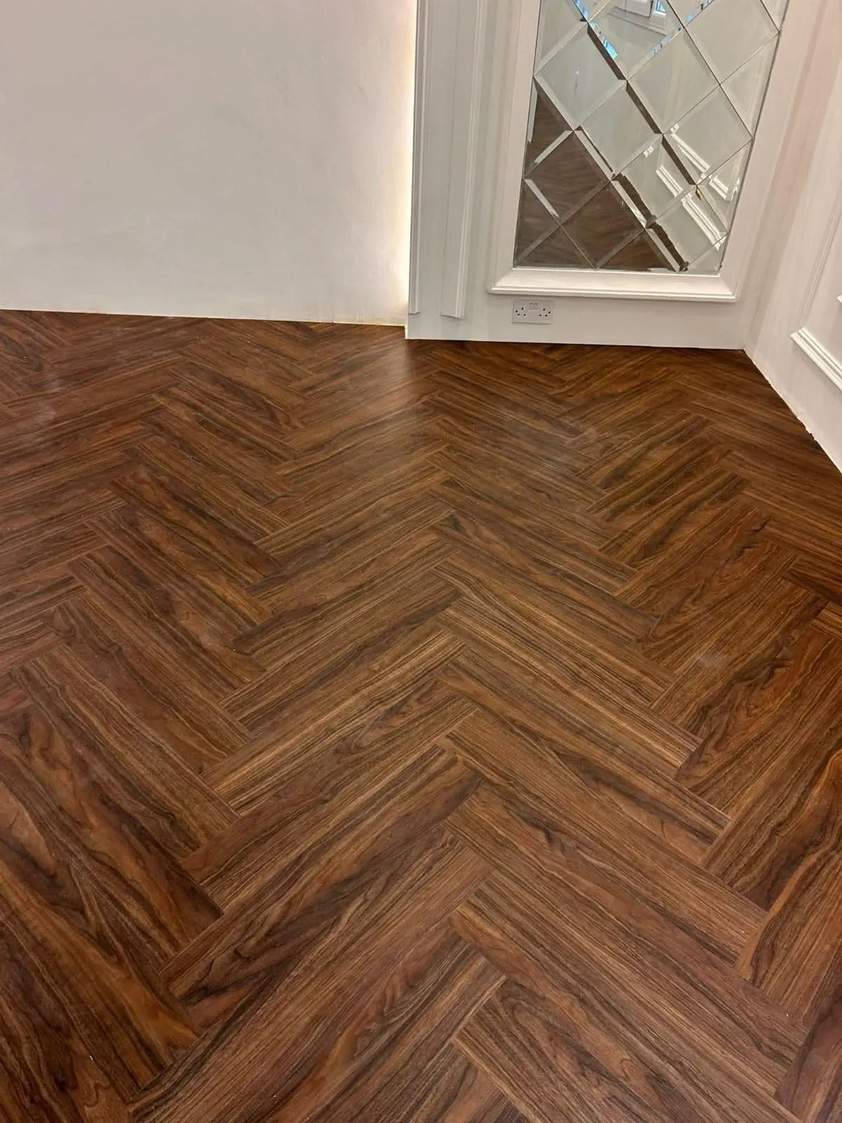 Herringbone wood-look flooring laid through a room corner