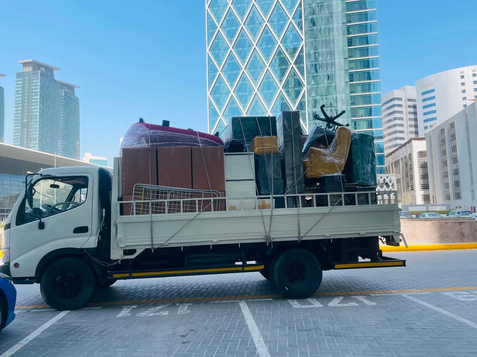 Truck loaded with wrapped office furniture in front of the West Bay towers, Doha