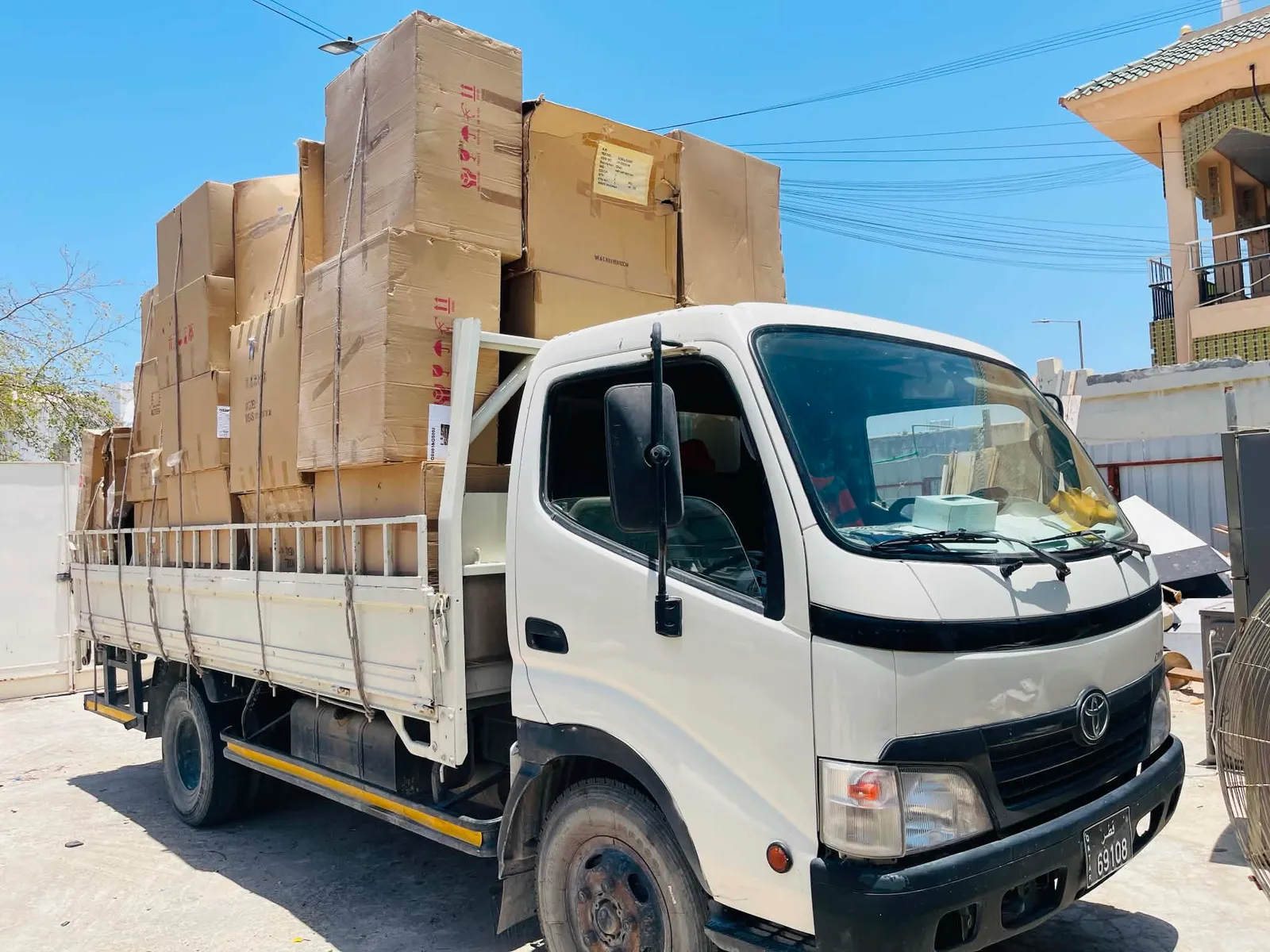 Flatbed truck stacked with packed cartons on a residential street in Qatar