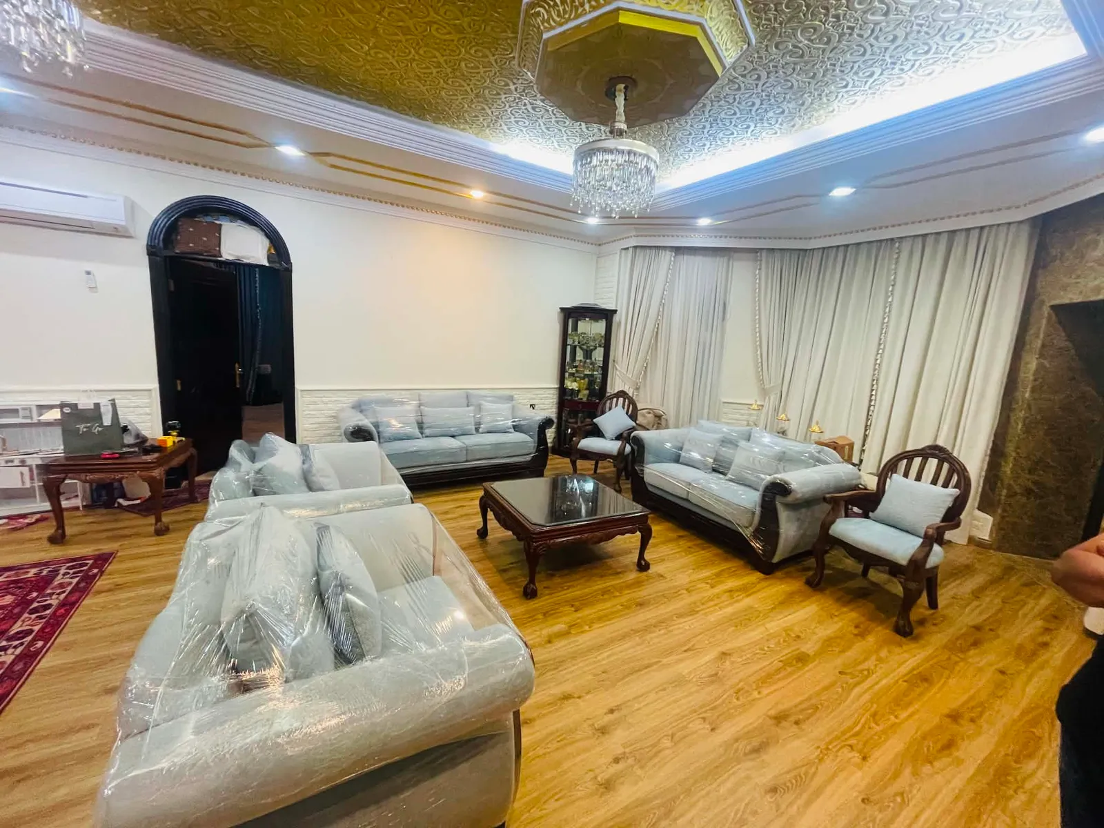 Reupholstered pale blue majlis seating beside full-height curtains