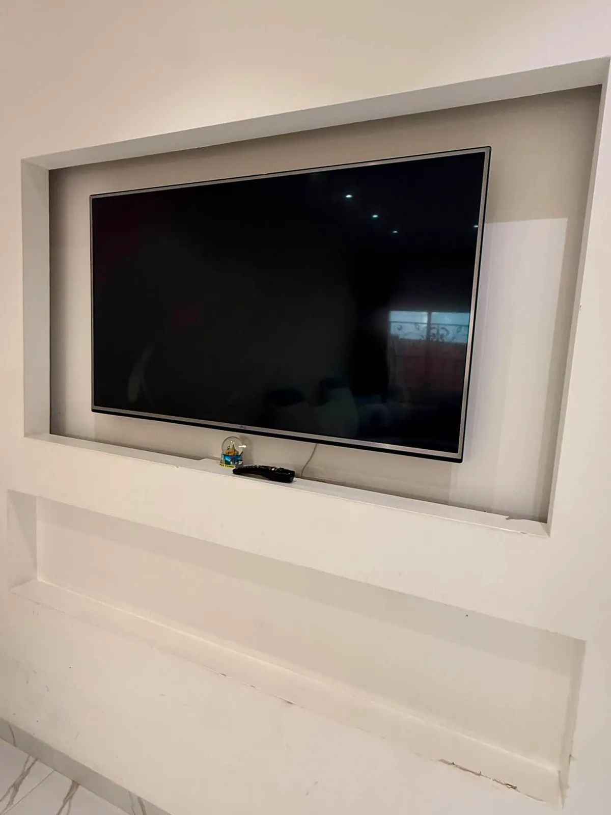 Television recessed into a built-in wall niche with a display ledge below